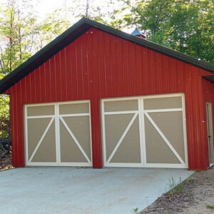 Red shed or garage building with double doors in tan and white. Cemenet pad infront of building